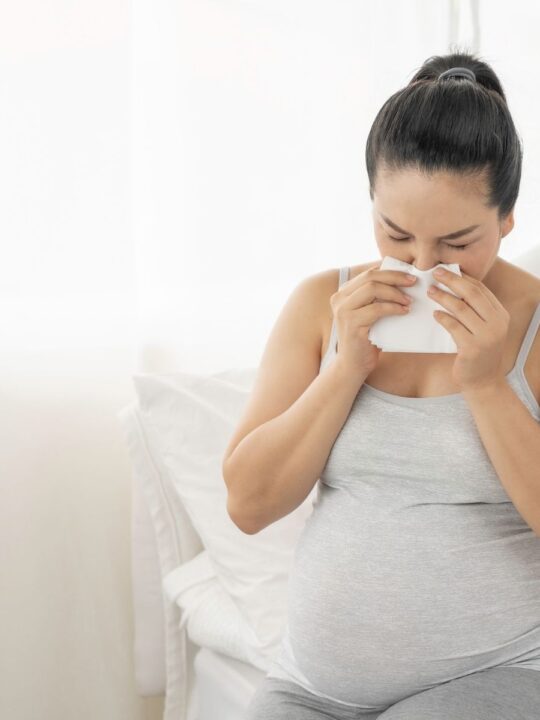 Sick pregnant woman blows her nose.