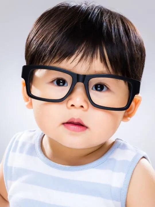 Baby boy wears black glasses.