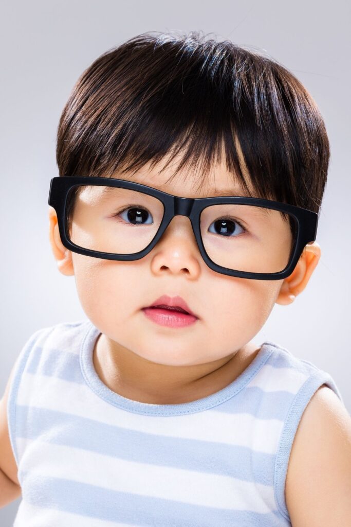 Baby boy wears black glasses.