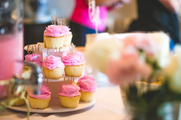 Pink cupcakes with gold toppers on a cupcake stand.