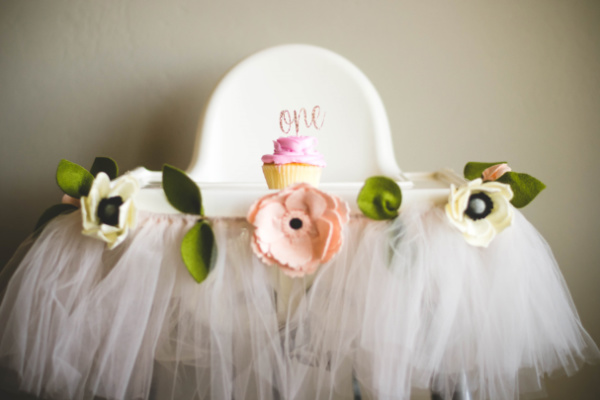Tulle and flower high chair decorations for a floral-themed first birthday party.