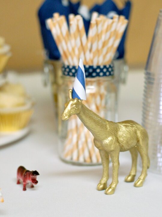 Gold plastic giraffe with party hat.