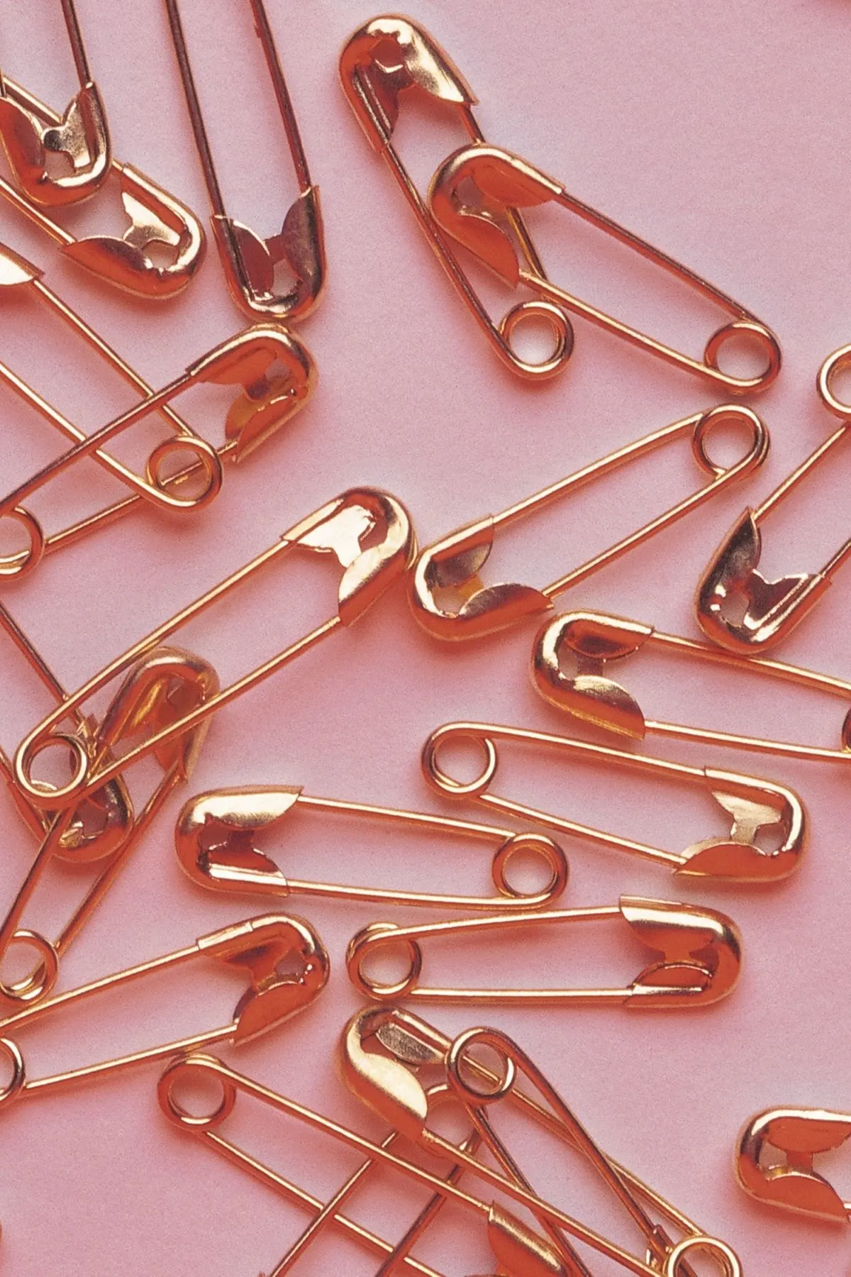 Gold safety pins on pink background.
