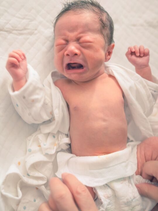 Newborn baby cries while getting diaper changed due to painful diaper rash.