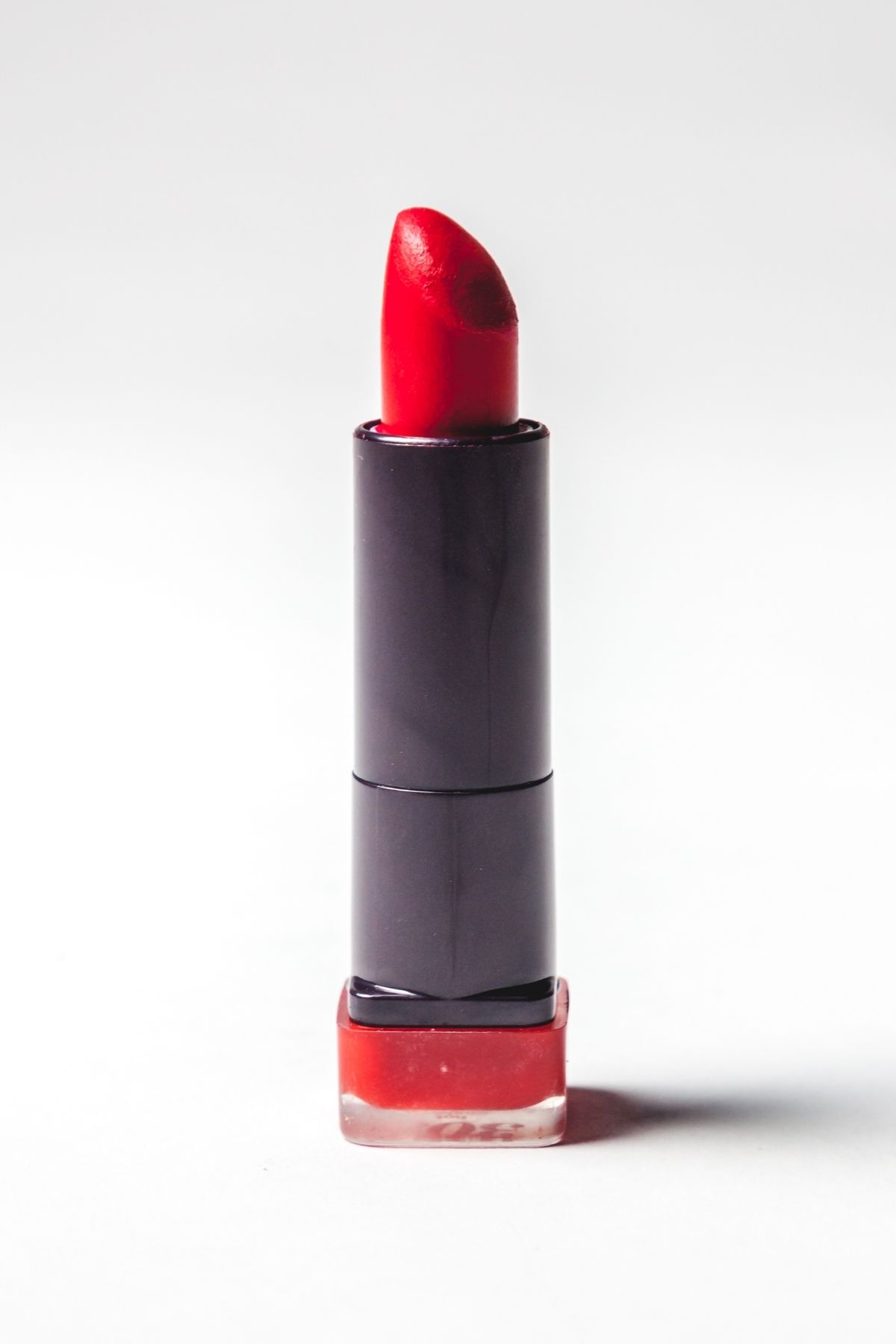 Red lipstick in a black tube in front of a white background.