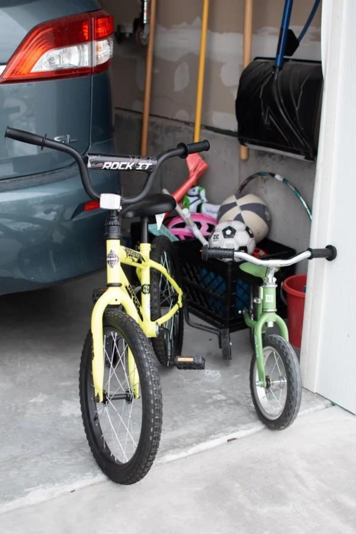 Yellow and green kids bikes parked inside garage in front of blue van.