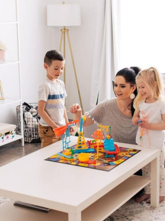 Mother and kids play with a board game gift on their living room coffee table.