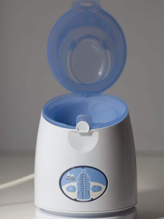 Blue and white baby bottle warming machine with an opened lid on white background.