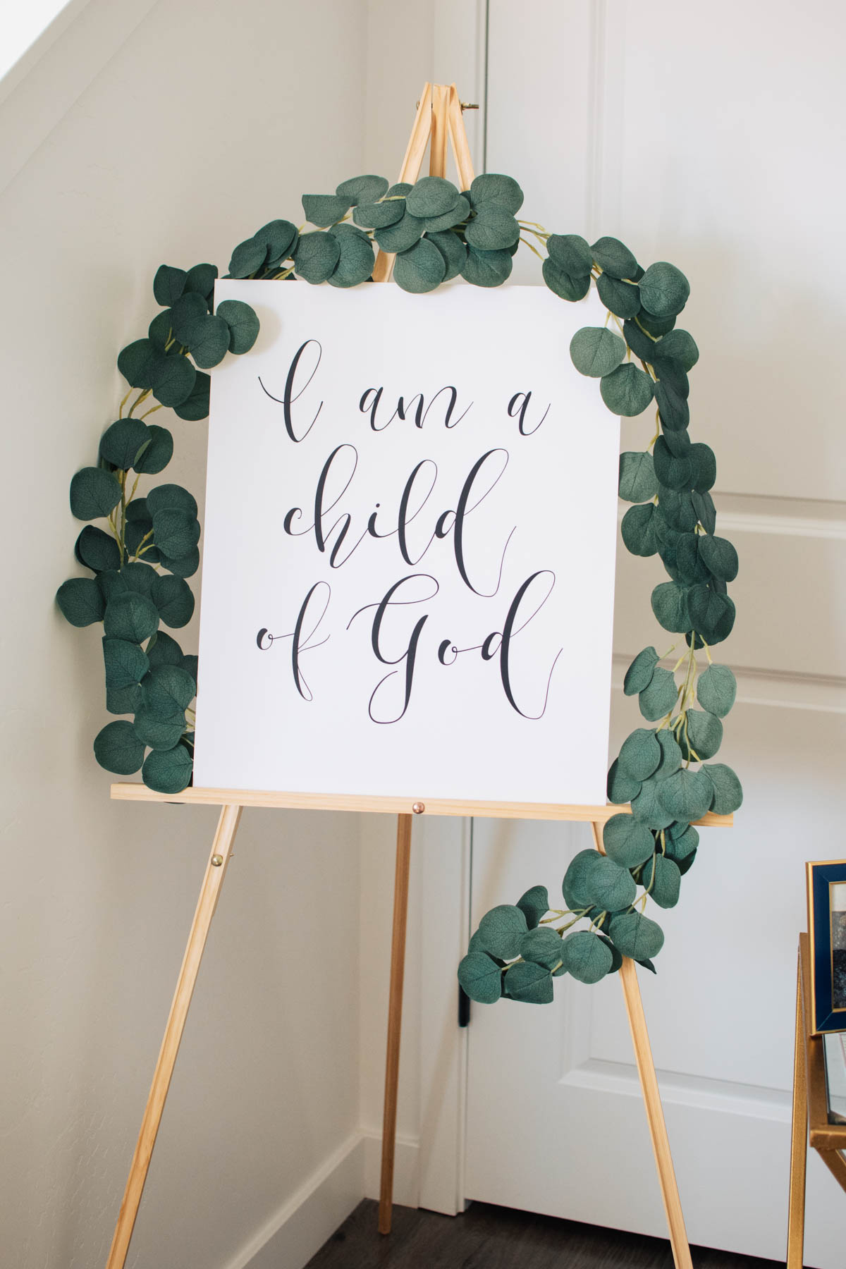 I am a child of God sign on wood easel with eucalyptus garland.