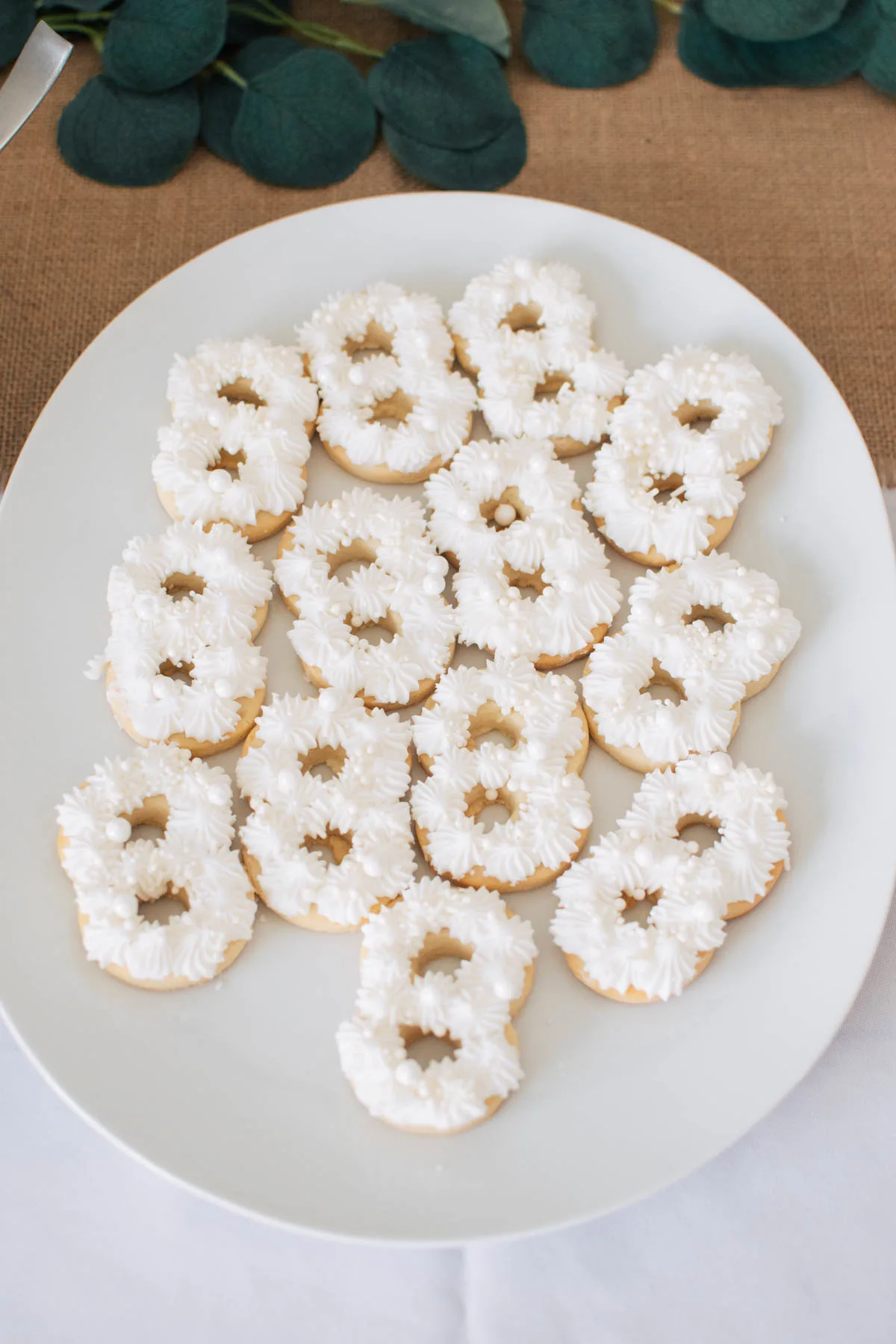 Several number 8 sugar cookies with white frosting and sprinkles on white platter.