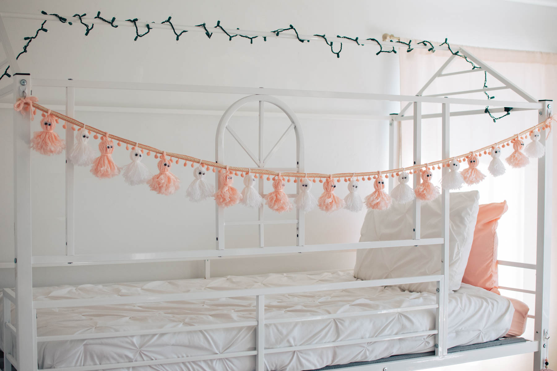 Pink and white ghost garland attached to white bunk bed.
