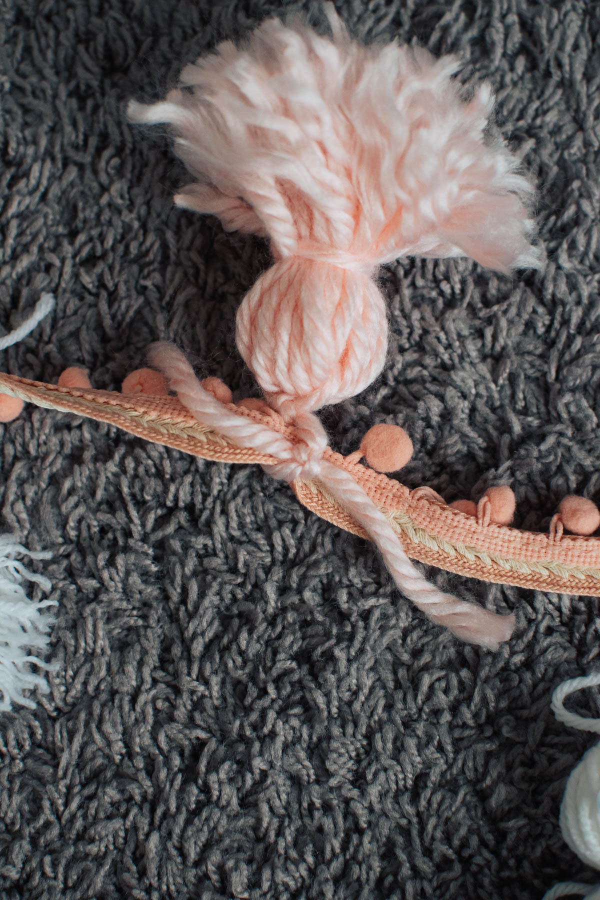 String from yarn ghost tied in knot on pom pom trim.