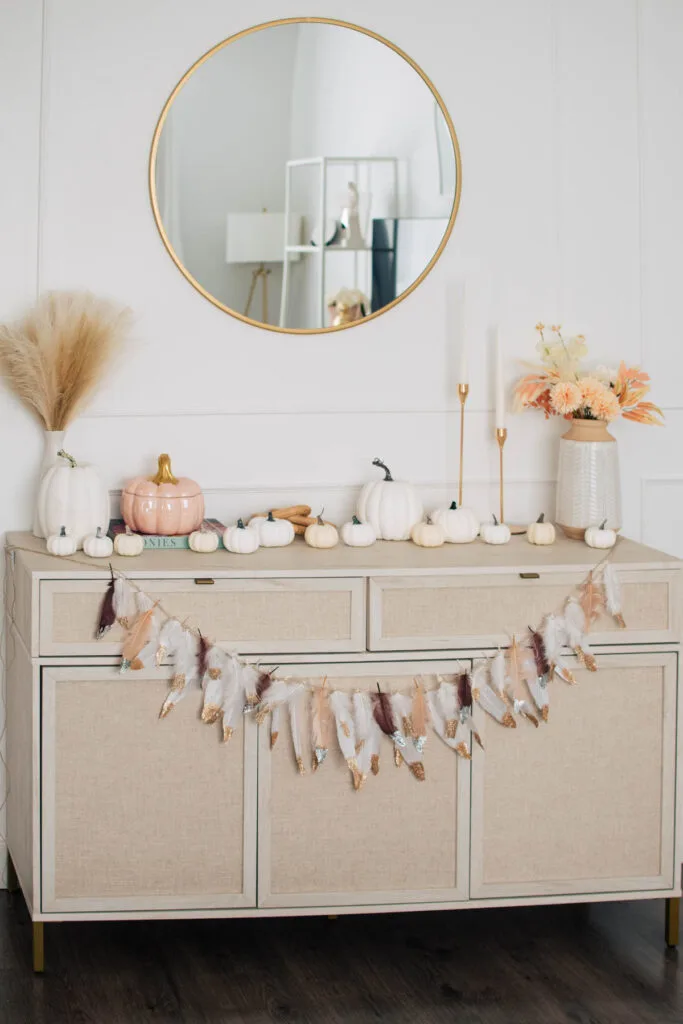 DIY fall garland made of feathers on cream colored sideboard.