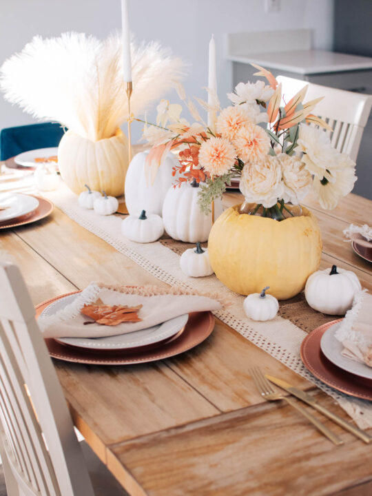 Modern Thanksgiving table decor with white pumpkins, pampas grass, and neutral colored plates.