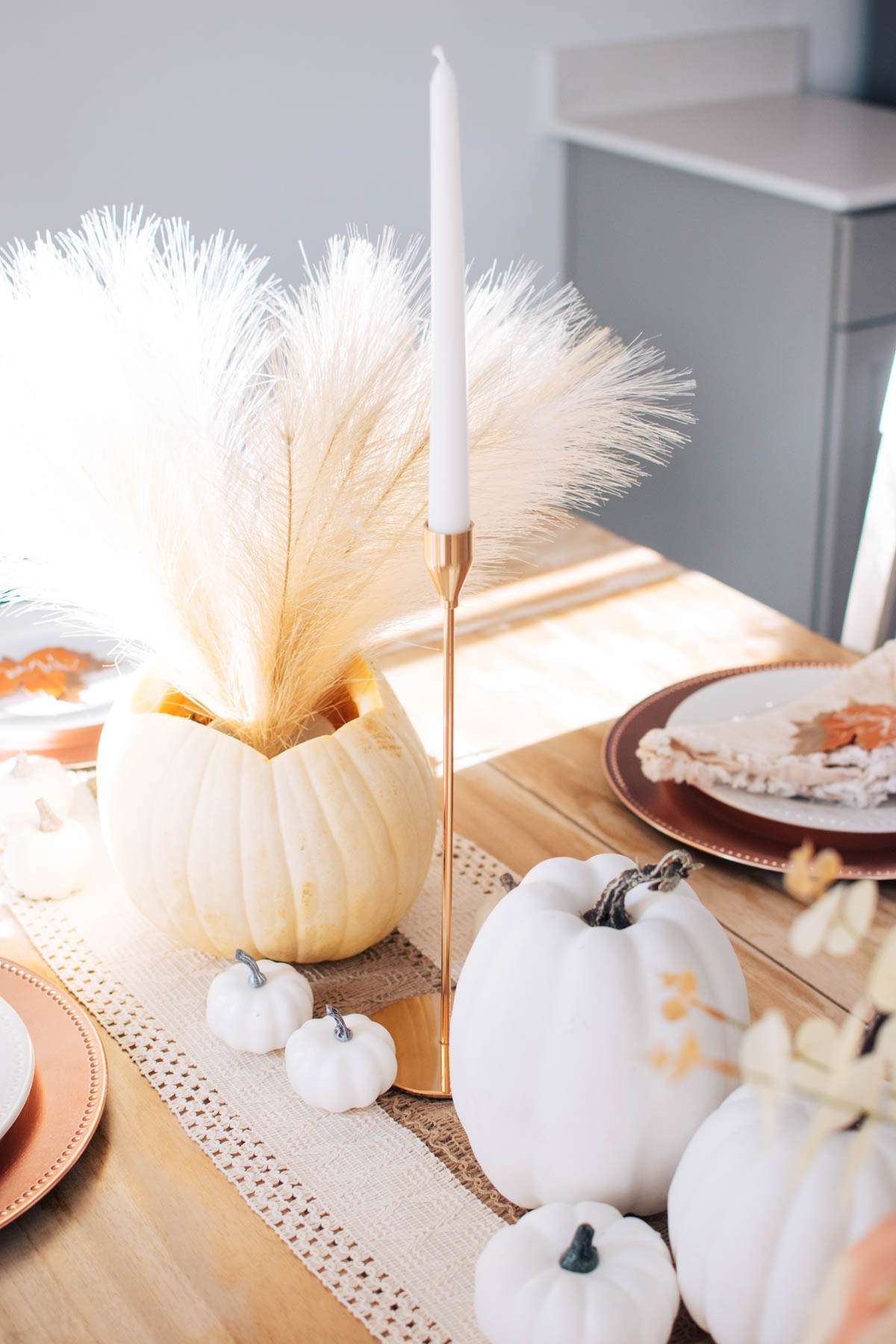 Simple Thanksgiving table decor including pampas grass bouquet and gold candle sticks.