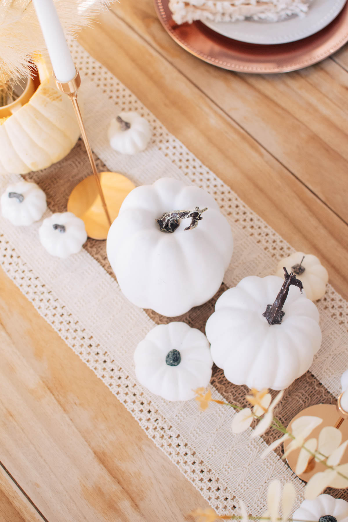 Thanksgiving table decor from Amazon including white pumpkins, table runner, and candle stick.