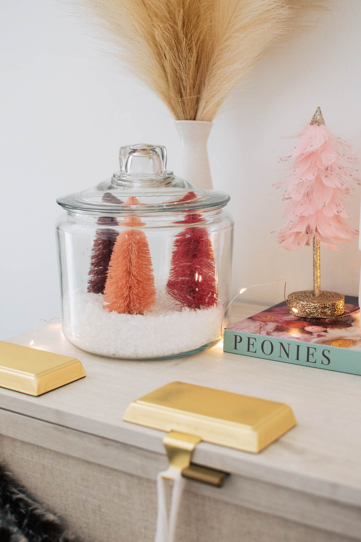 Pink bottle brush Christmas trees and fake snow in glass cookie jar.