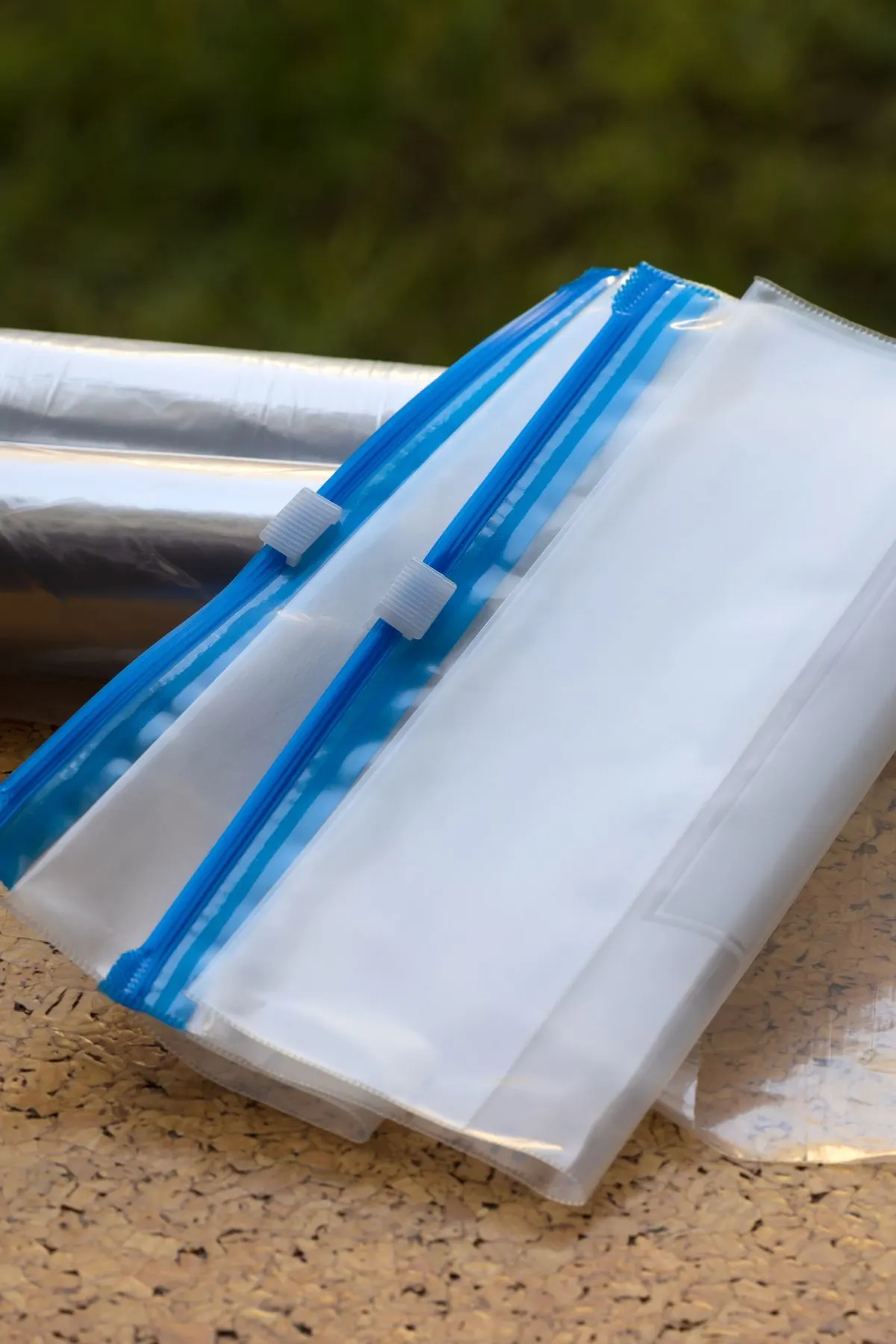 Pile of Ziploc storage bags with blue trim on a counter with plastic wrap.