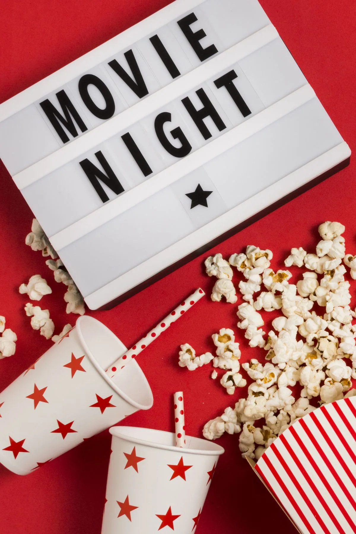 Movie night sign on a red background with a bag of popcorn and drinks.