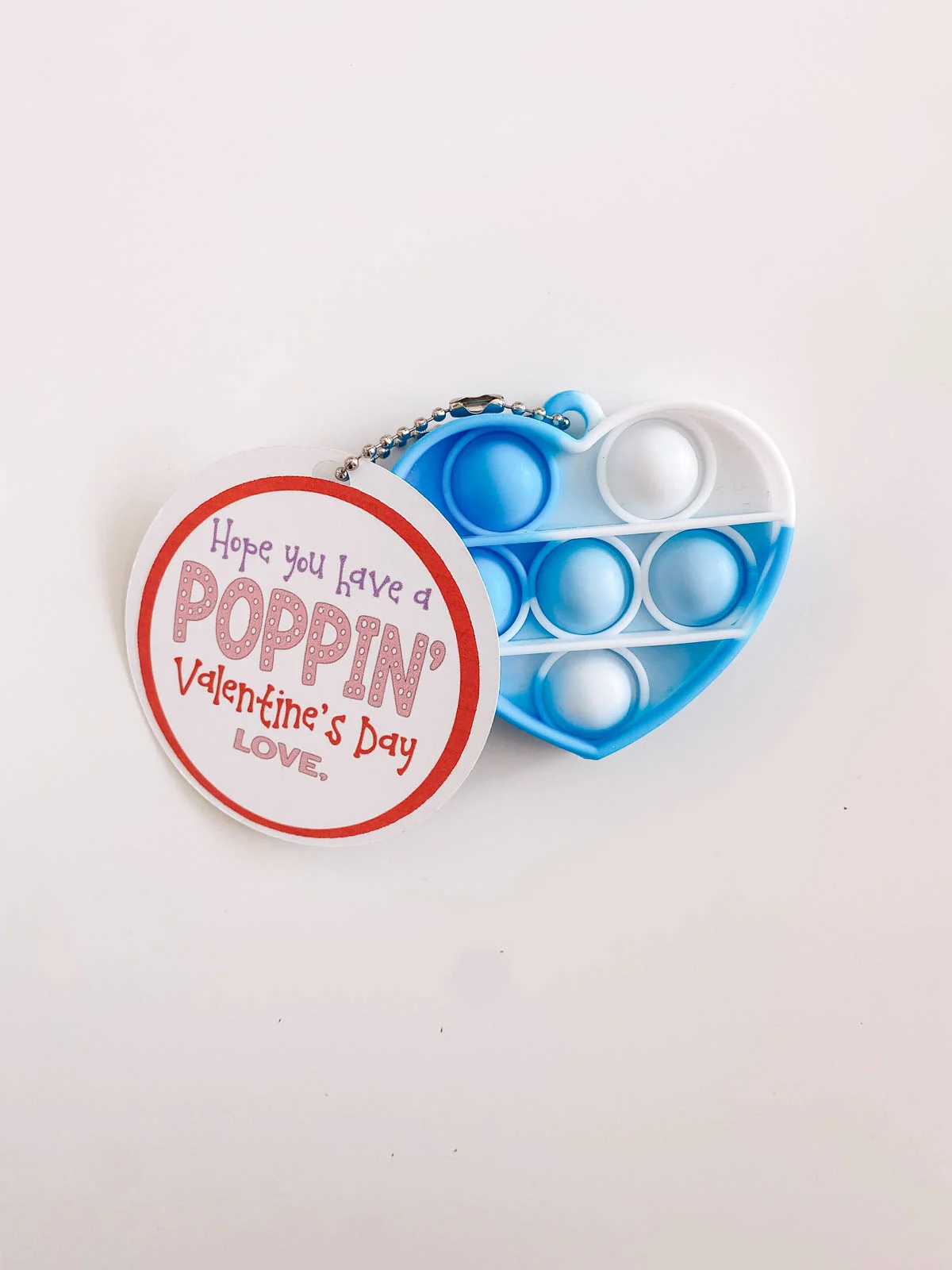 Heart-shaped pop fidget toy valentine with tag on a kitchen counter.