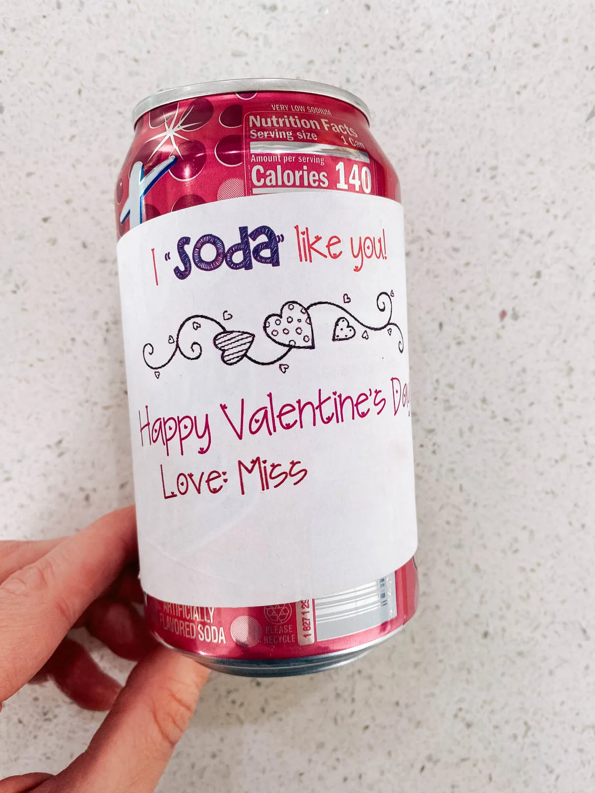 Pink can of soda with a Valentine's day message on a piece of paper wrapped around it.