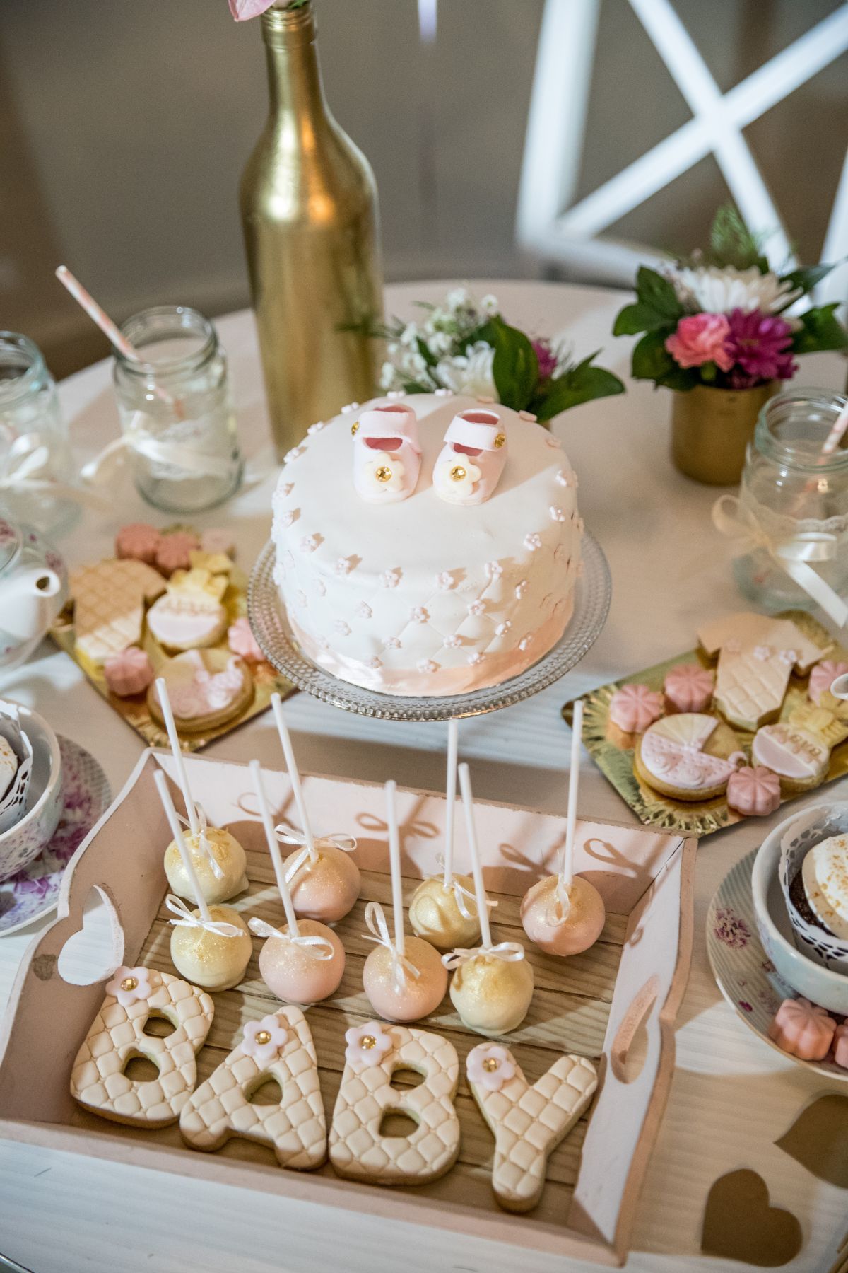 A dessert table at a baby shower with cake, cookies, and cake pops.