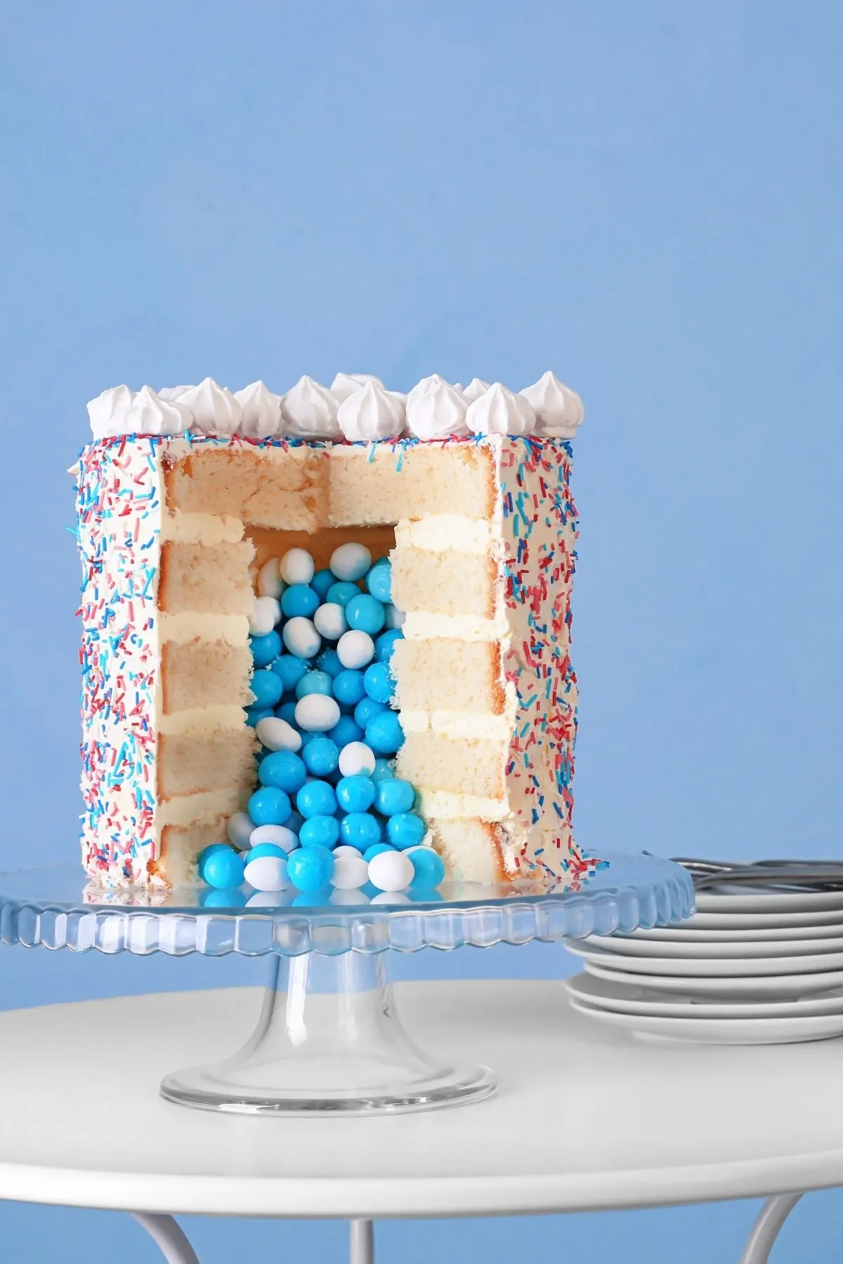 Blue candies spill from a cake with a large slice taken out of it.