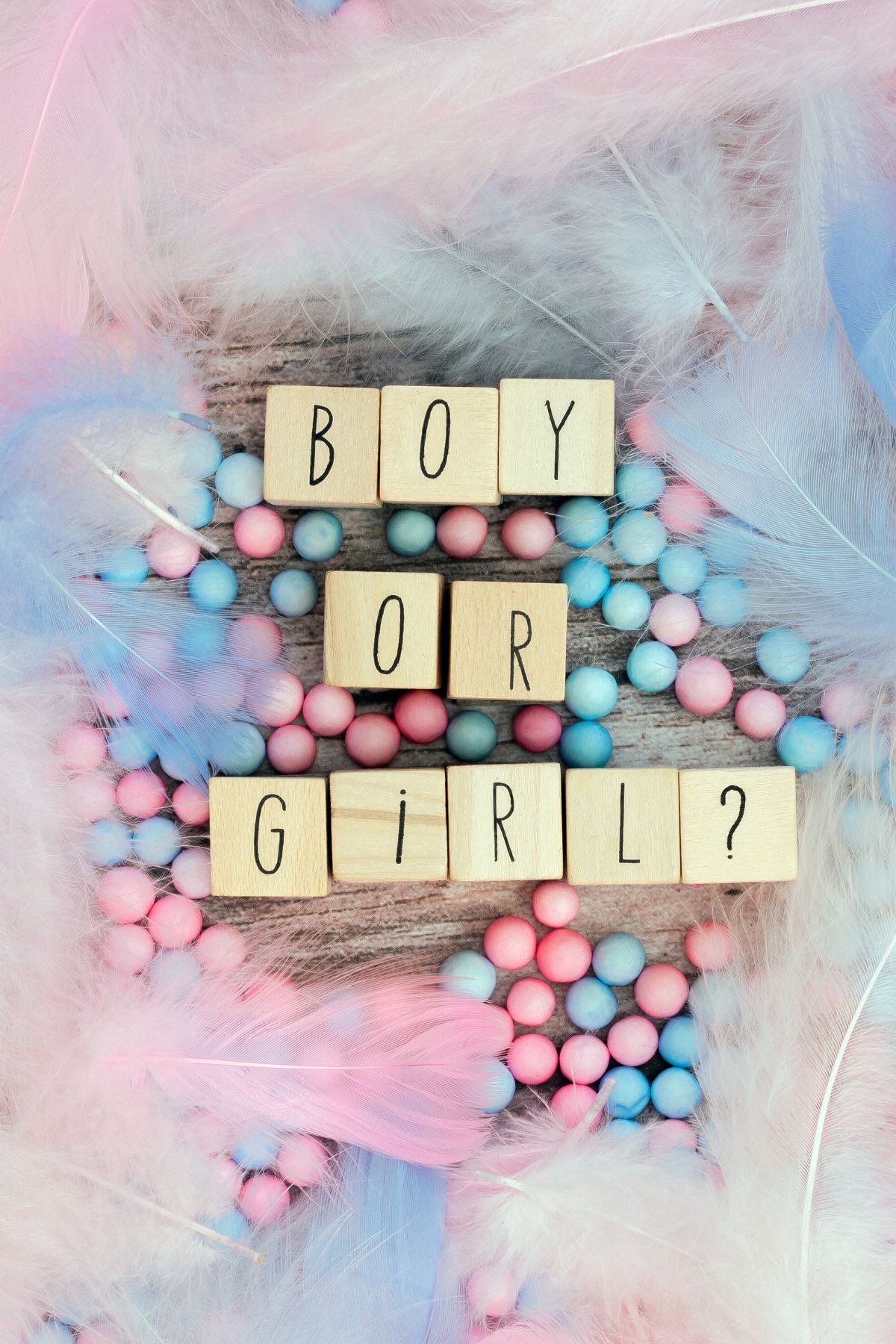 Wooden blocks that spell boy or girl over pink and blue decorations.