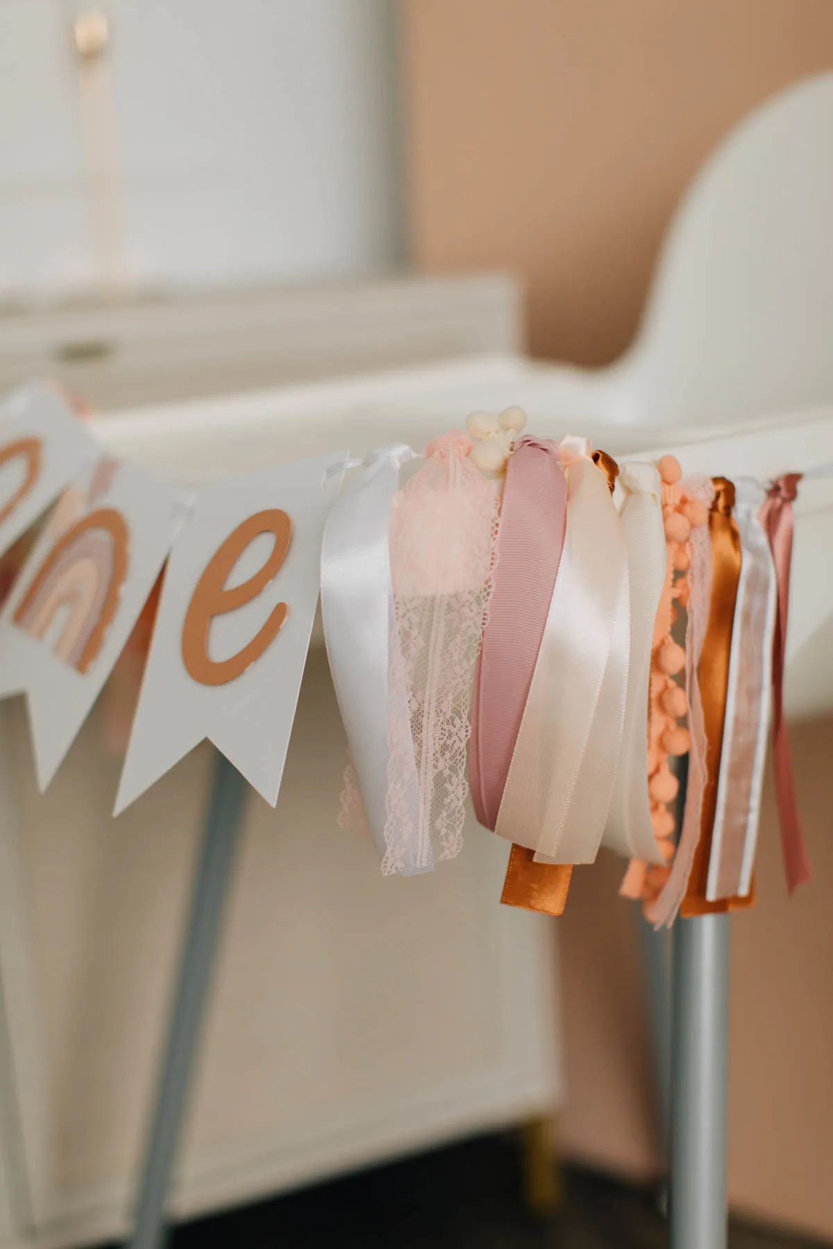 Boho colored ribbons on birthday party high chair banner.