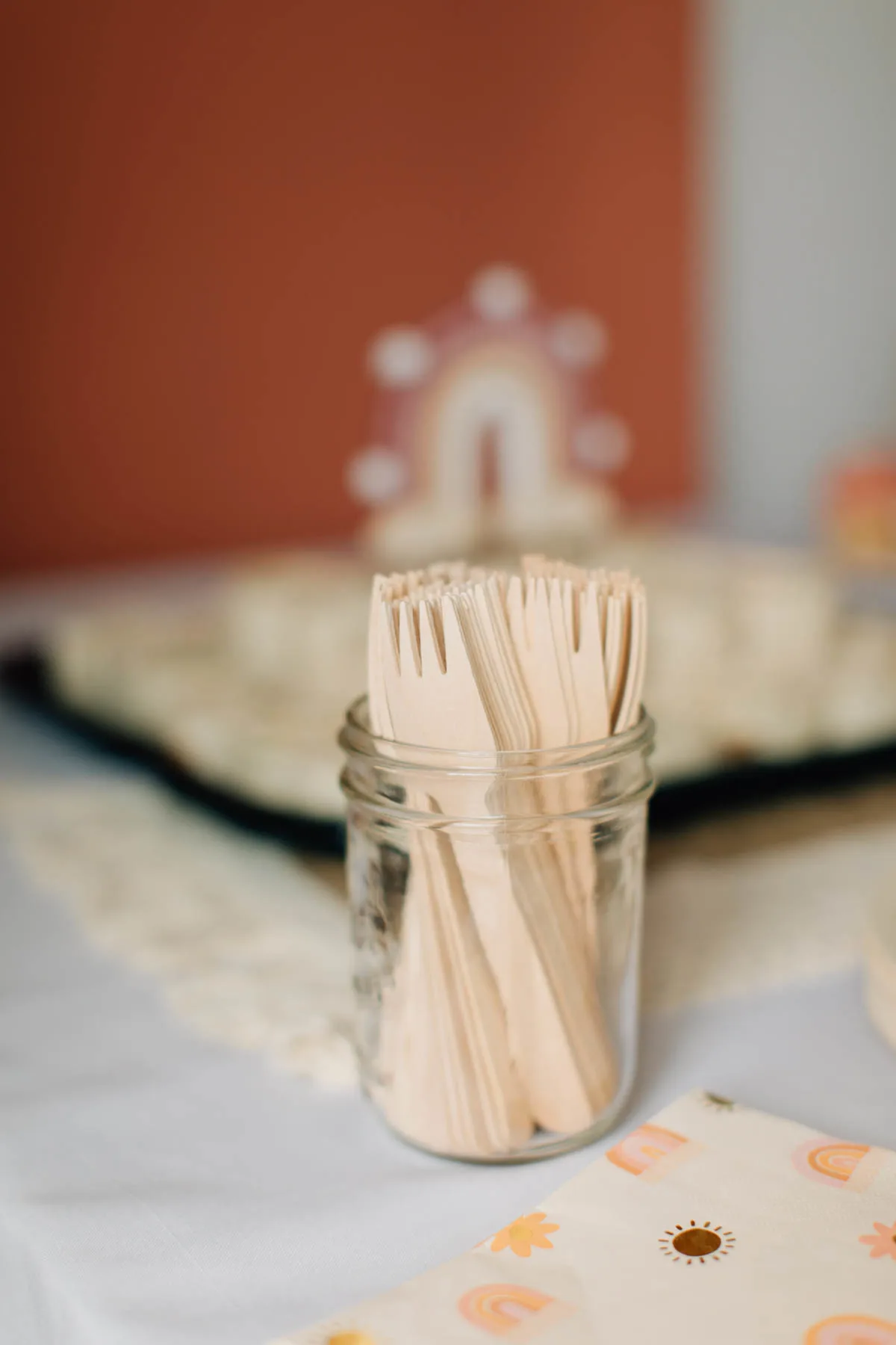 Wood forks in glass mason jar on food table.