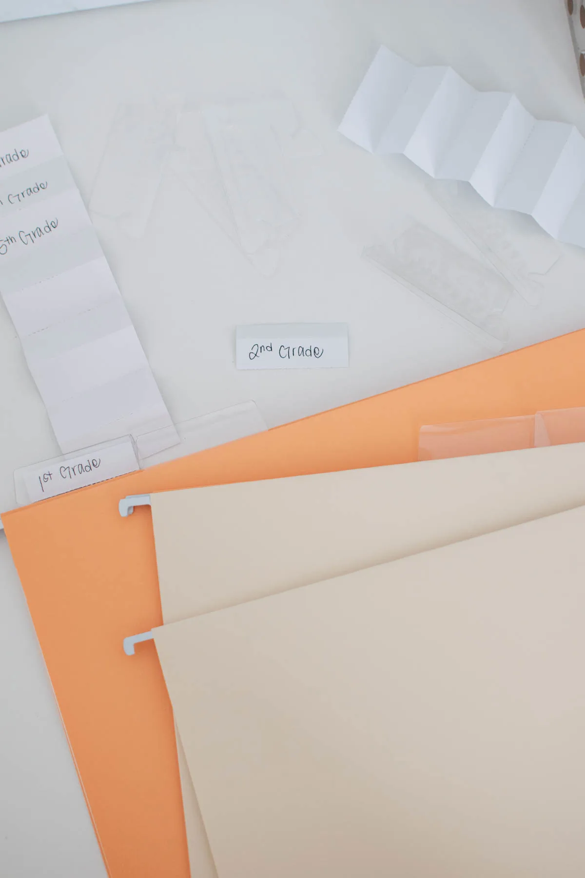 File folders, white labels, and plastic tabs on white desk.