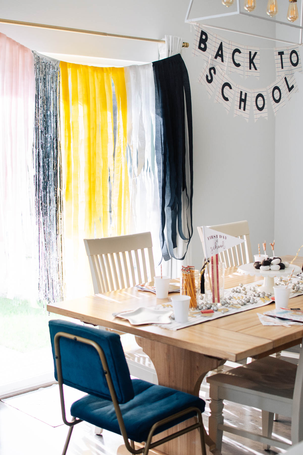 Back to school backdrop with a pencil color pattern hangs behind kitchen table decorated for back to school.