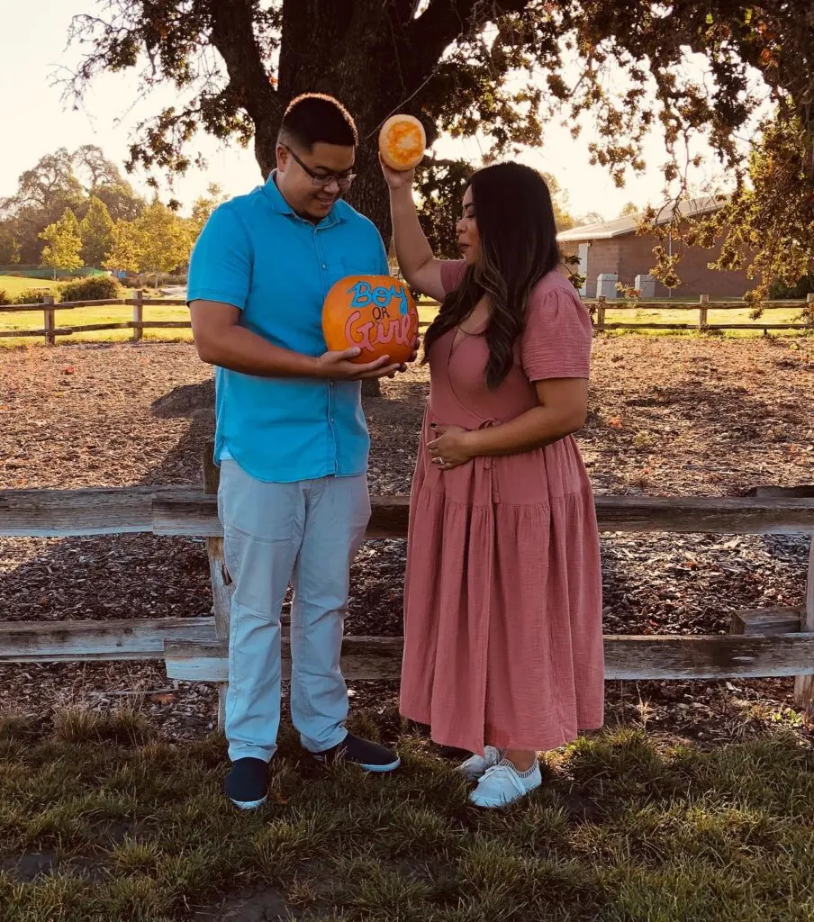 A couple looks inside of a painted pumpkin to discover the gender of their baby.