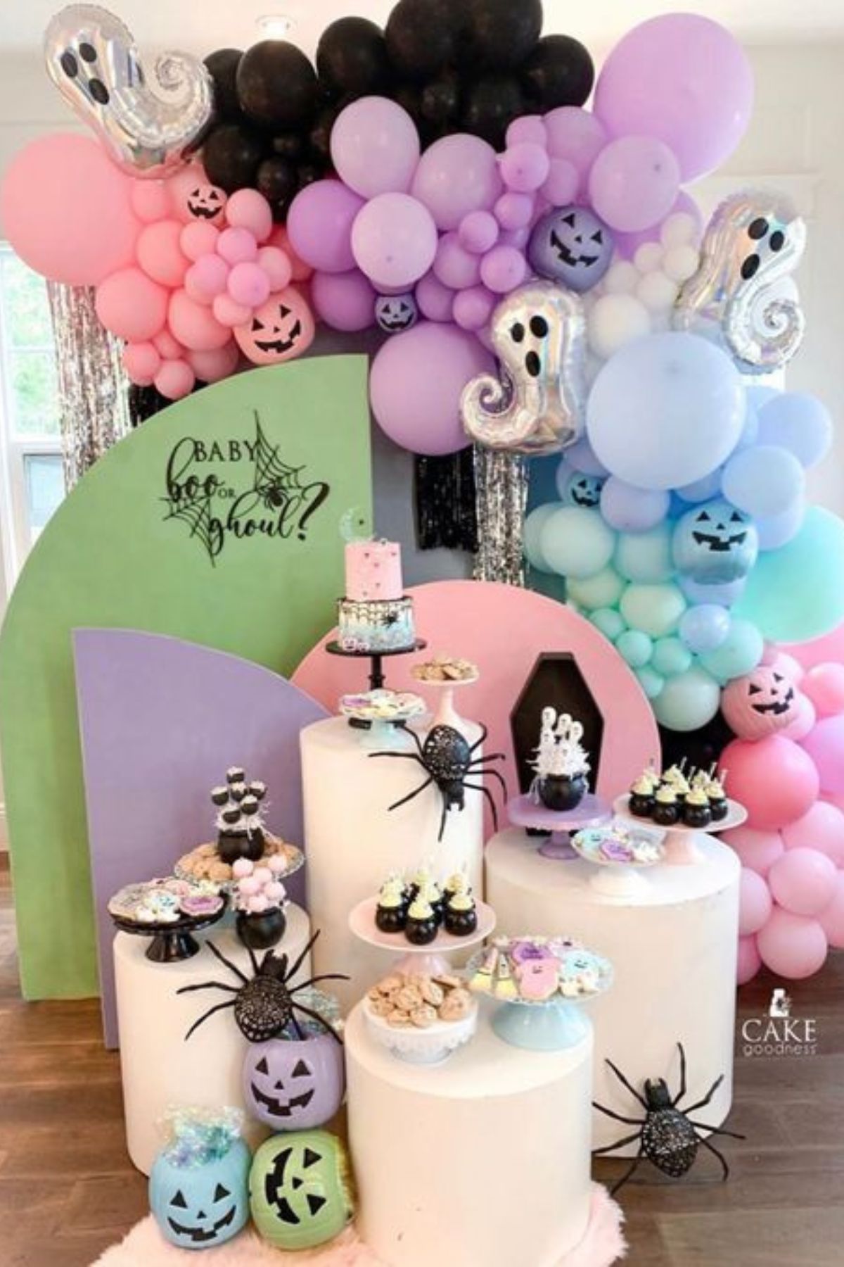 A Halloween gender reveal backdrop with pink, purple, and blue balloons and spooky decorations.