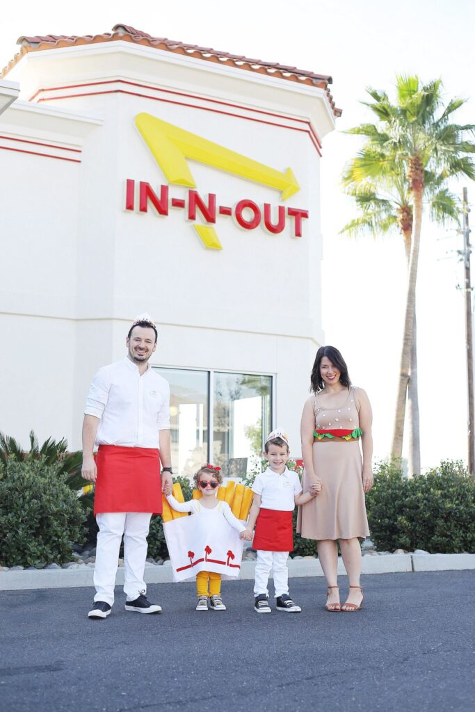 Family of 4 wearing In-n-Out inspired costumes stands in front of In-n-Out restaurant.