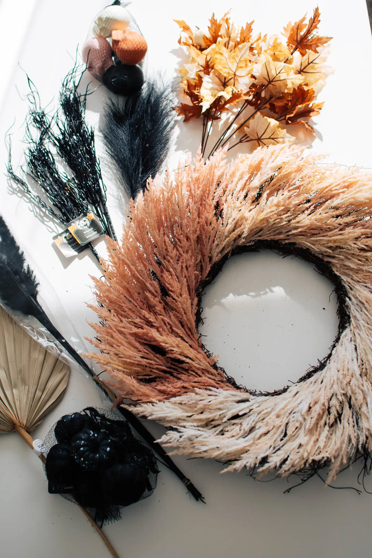 Supplies to make a Halloween wreath including pampas grass, skulls, and leaves.