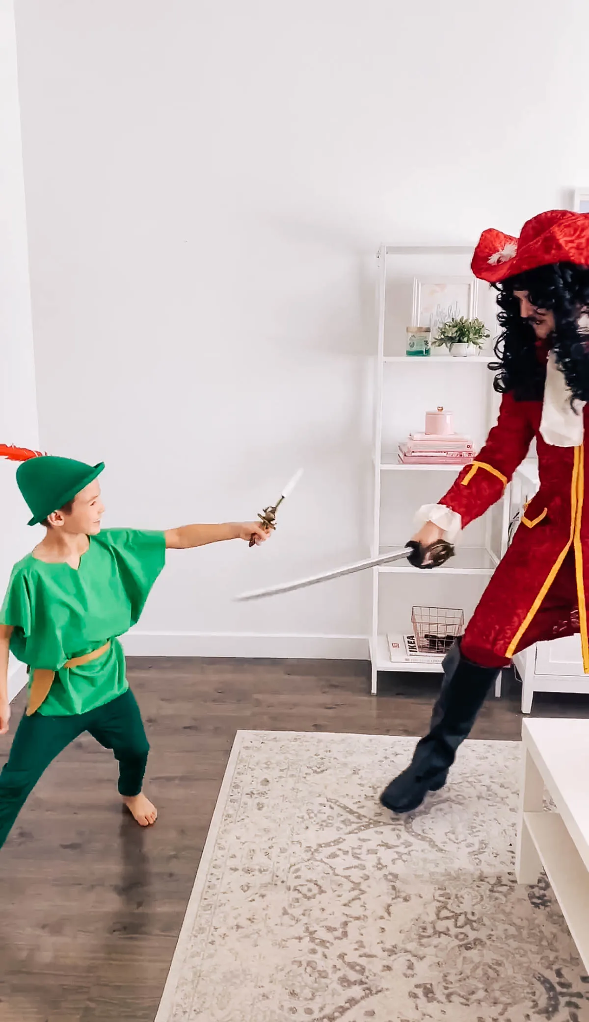 Boy dressed as Peter Pan pretends to fight with man dressed as Captain Hook.