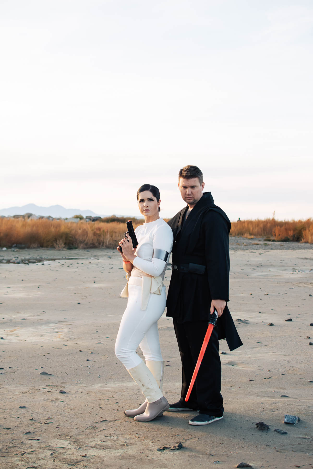 Woman dressed as Padme holds gun and stands next to man dressed as Anakin.