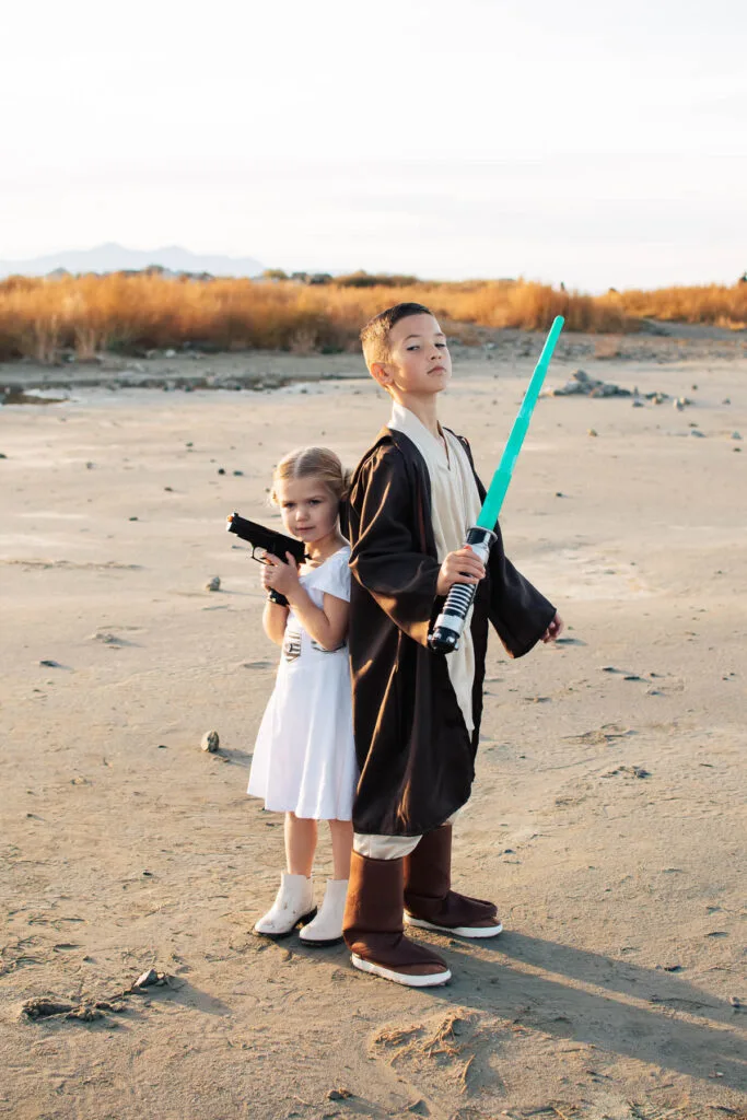 Girl dressed as Princess Leia stands back to back with boy dressed as Luke Skywalker.