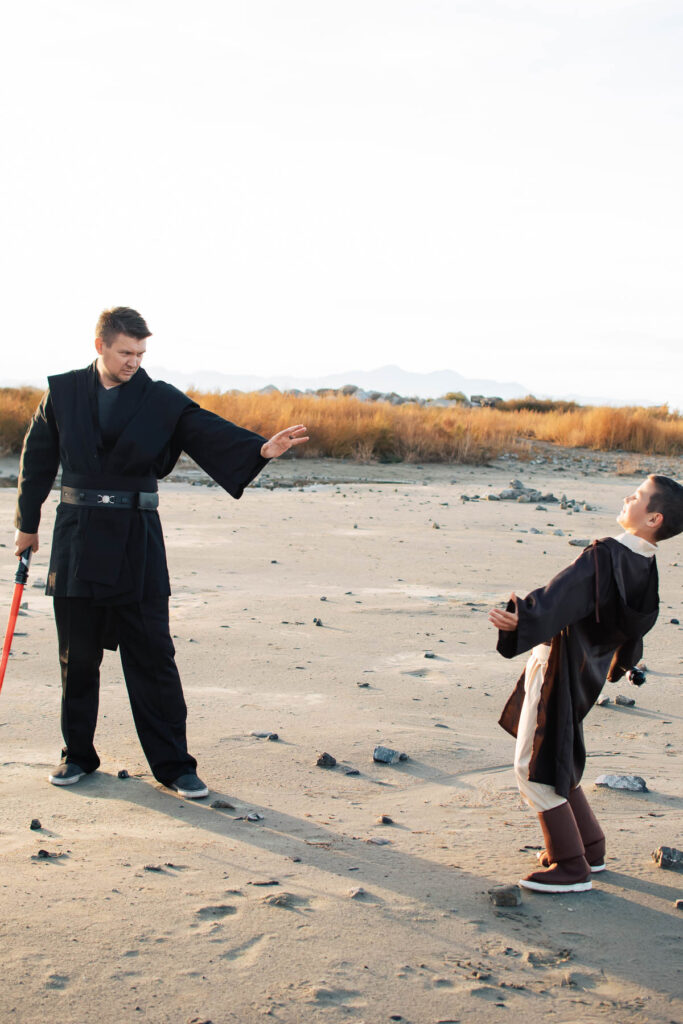 Man dressed as Anakin pretends to use the force on boy dressed as Luke.