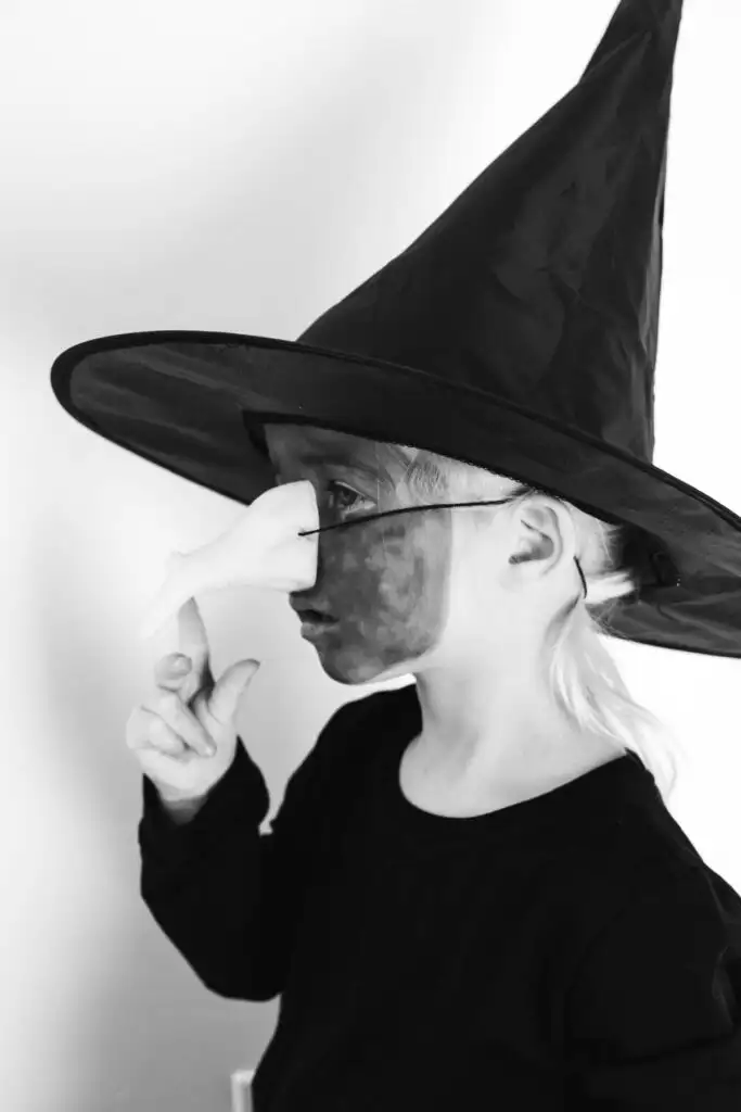 Black and white photo of profile of little girl dressed as the Wicked Witch.