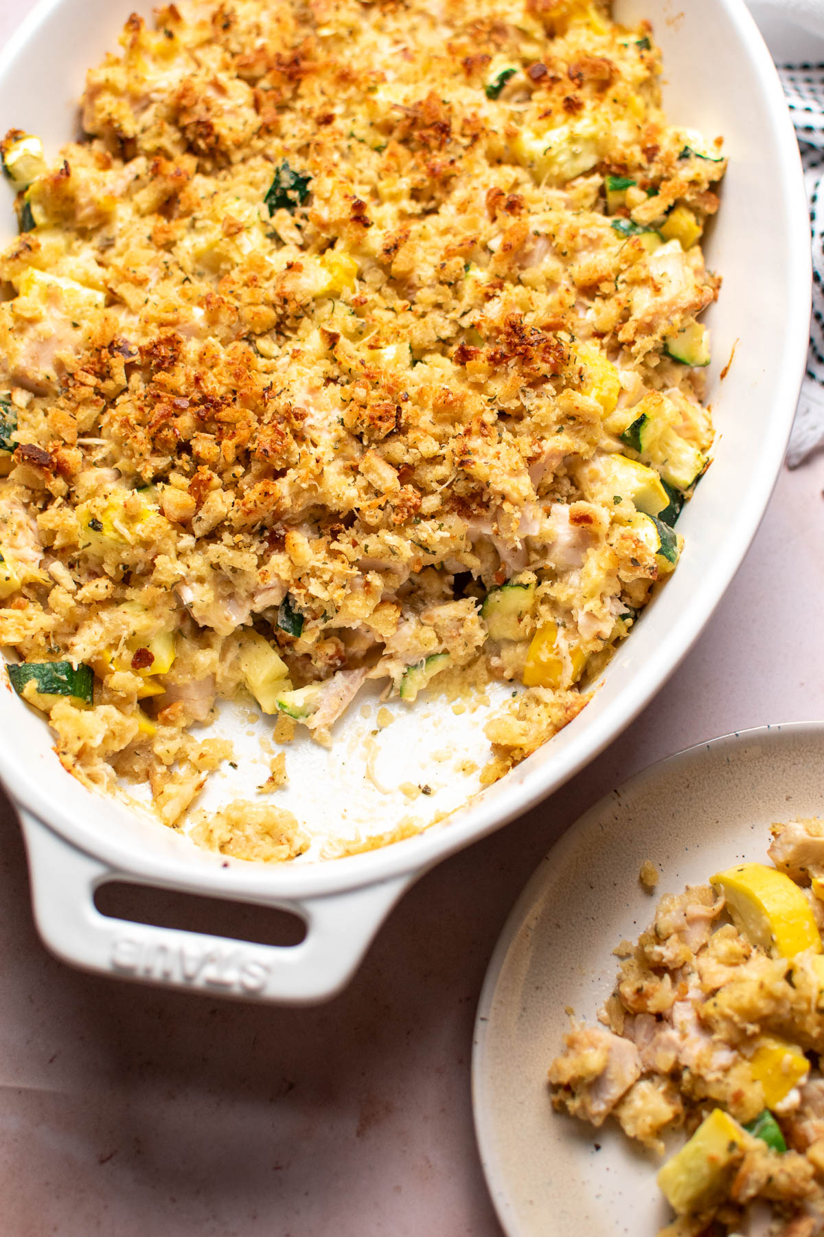 White baking dish of chicken zucchini casserole with a scoop taken out.