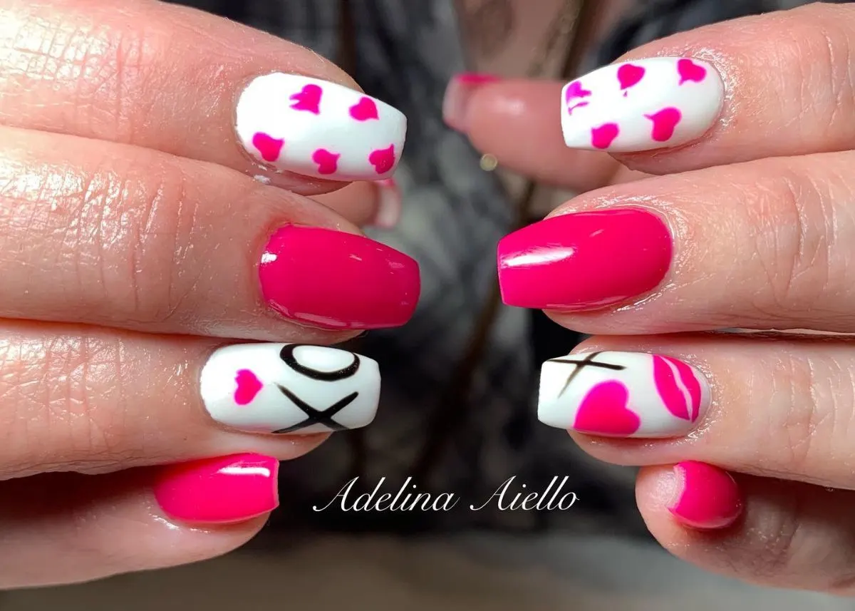 Pink and white Valentine's Day nails with mini heart and "xoxo" designs.
