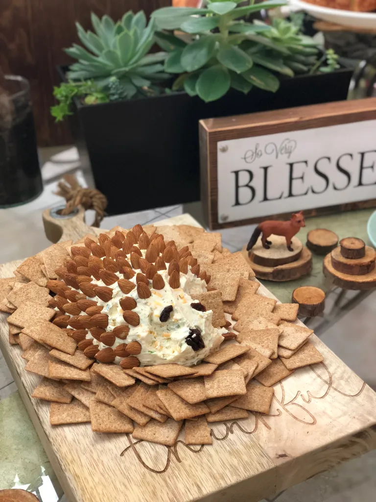 A cheeseball with almonds made too look like a hedgehog with crackers all around.