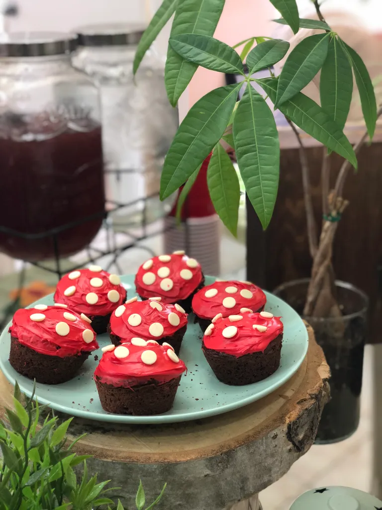 Several cupcakes with red frosting and white dots to look like mushrooms.