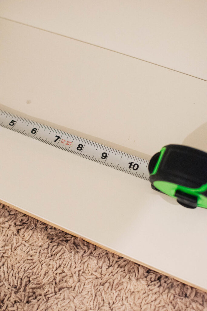 Green measuring tape rests on piece of white wood.