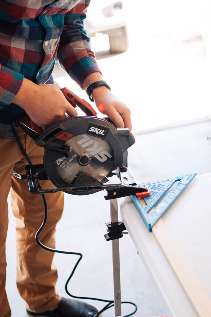 Man uses circular saw to cut piece of wood trim held in place with clamp.