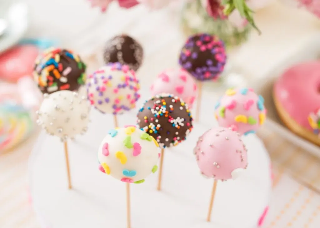 Pink, white, and brown cake pops with sprinkles.