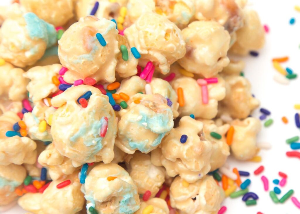 Popcorn with different colored sprinkles on a white background.