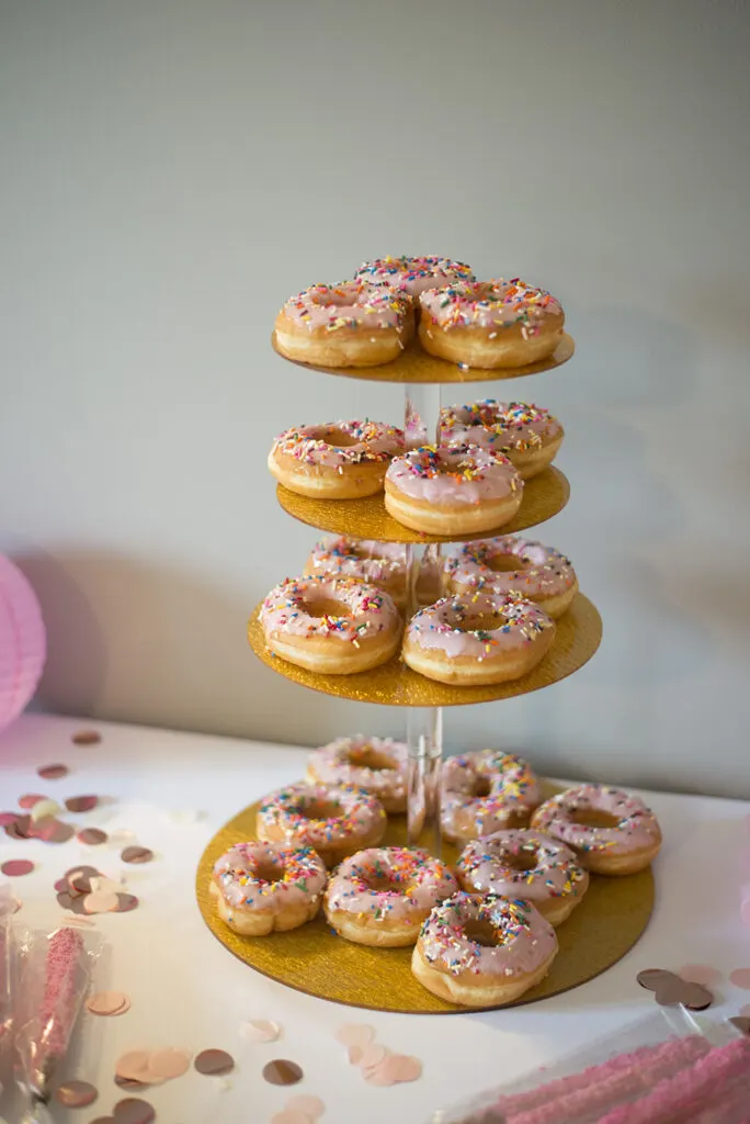 A tower of donuts with sprinkles on a dessert table.